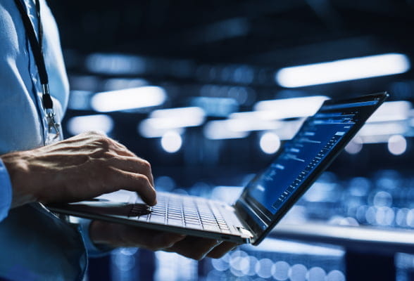 Trader holding an open laptop that displays stock market information on the screen